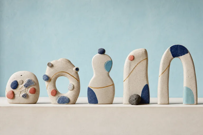 Five unlabeled ceramic markers grow quieter and steadier along one gently rising gold inlay.